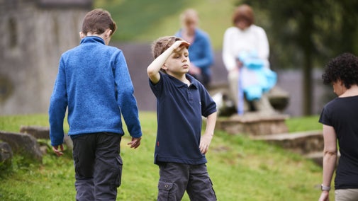 Two young boys are playing outside at Ilam Park, which contains lush green grass.